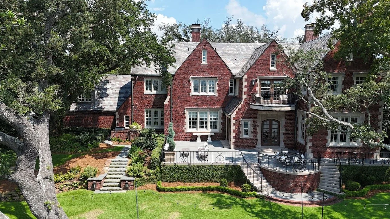 Grand brick Tudor home framed by mature live oaks